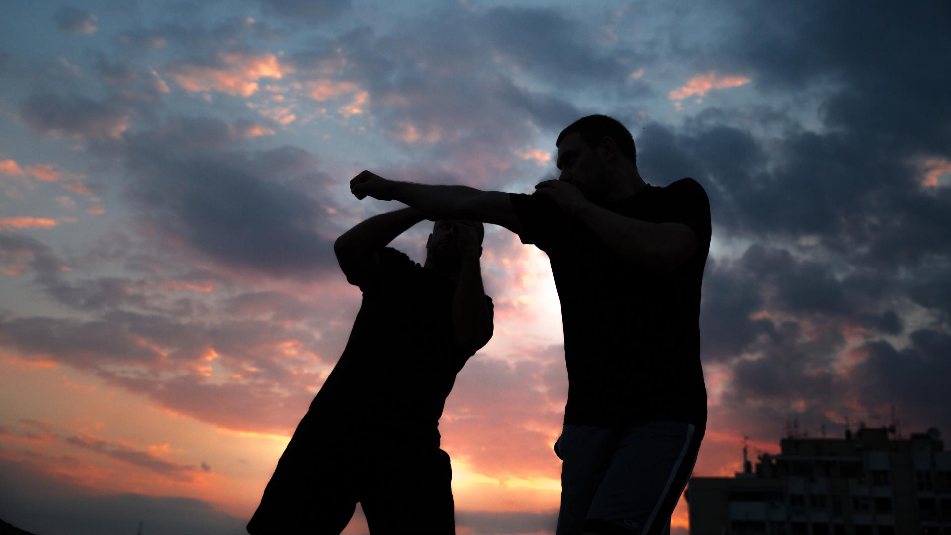 Pratiquant de Krav Maga en tenue complète, montrant des gants, un protège-dents, et des protège-tibias.